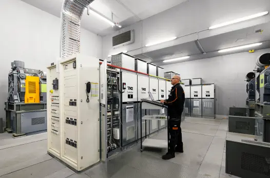 
TK Elevator Techniker in einem Maschinenraum mit Aufzug-Steuerungen
